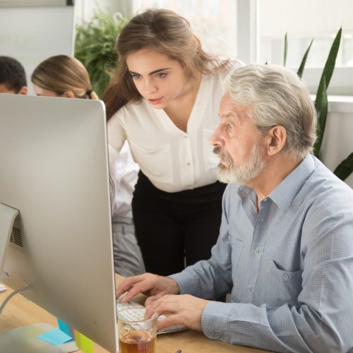 Female executive teaching senior office worker helping explainin